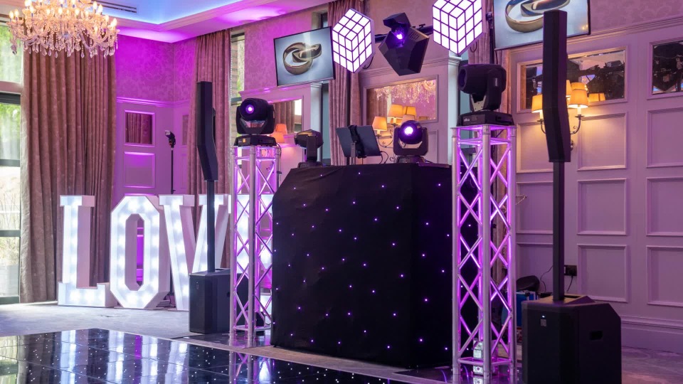 Premium black starlit DJ booth setup with pink uplighting, light truss and illuminated LOVE letters
