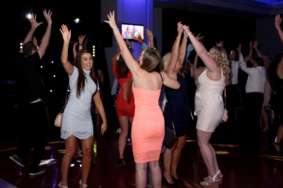 Group of women dancing with hands raised on dark dance floor at evening private party
