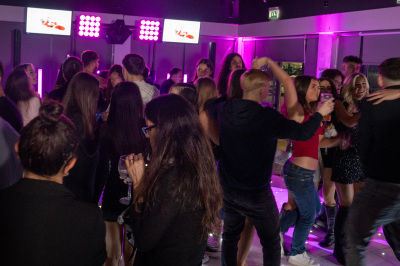 Crowd dancing in front of pink LED screen displays at modern bar party venue
