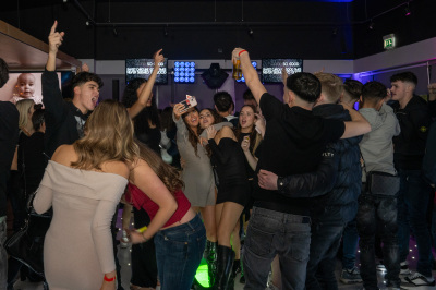 Crowd dancing with hands raised in front of blue LED video screens at modern bar venue