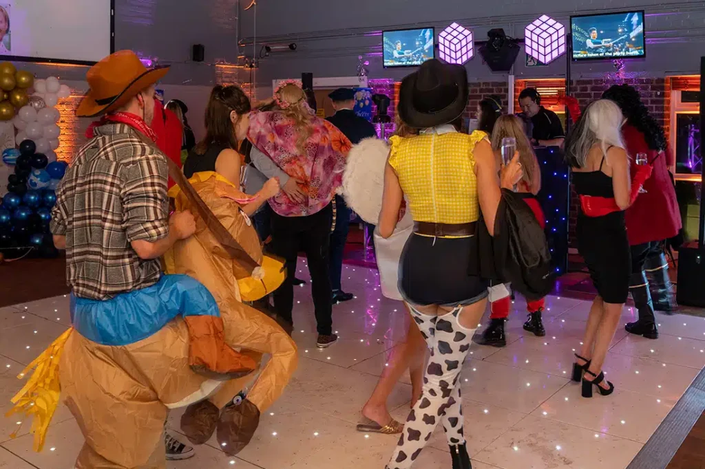 Themed fancy dress party dancers on white starlit dance floor with illuminated cube speakers