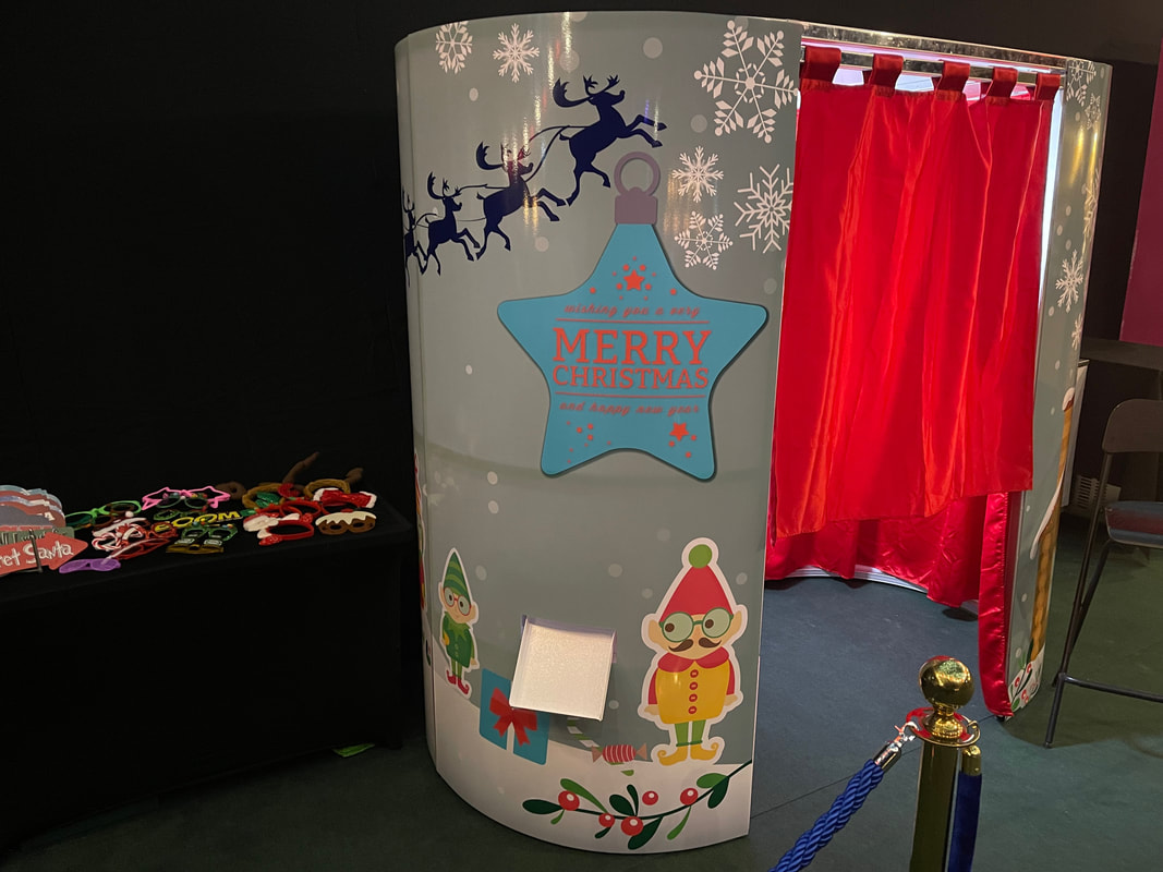 Disctilldawn Events photo booth dressed in Christmas-themed skins with snowflakes, reindeer and 'Merry Christmas' star, alongside a props table