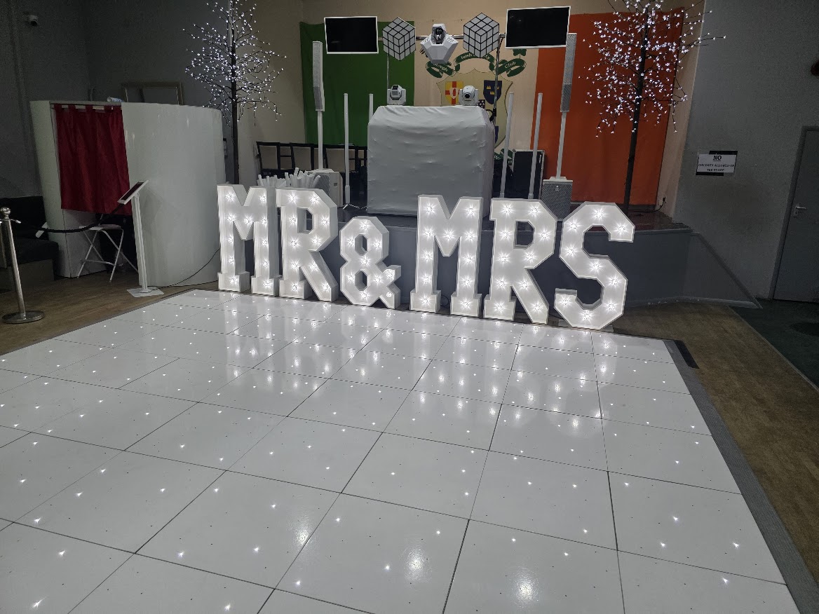 Light-up MR & MRS letters on a white starlit dance floor for a wedding ceremony