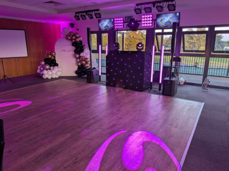 Disctilldawn premium disco DJ booth with pink uplighters, TV screens and balloon backdrop in a bright function room
