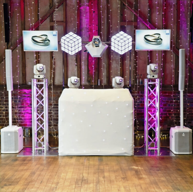 Disctilldawn Events premium wedding DJ setup with white starlit booth, truss lighting, white speakers and wedding ring displays on TV screens