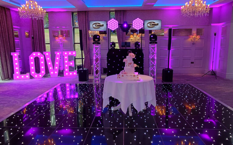 Wedding LOVE letters with wedding cake on starlit dance floor and TV screens at the DJ booth