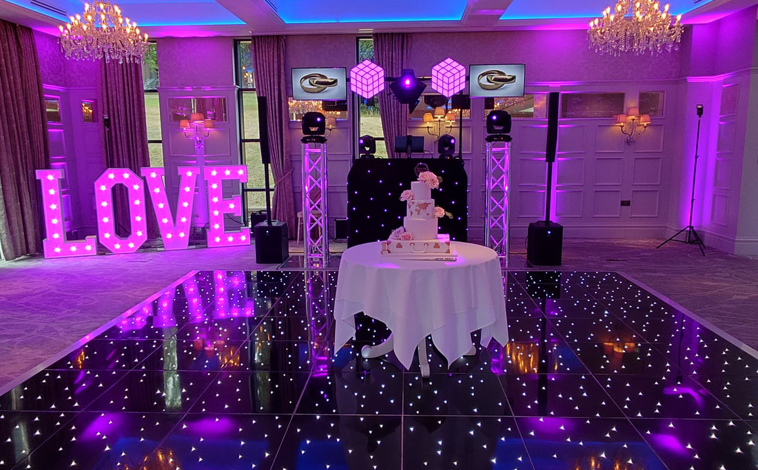 Wedding LOVE letters with wedding cake on starlit dance floor and TV screens at the DJ booth