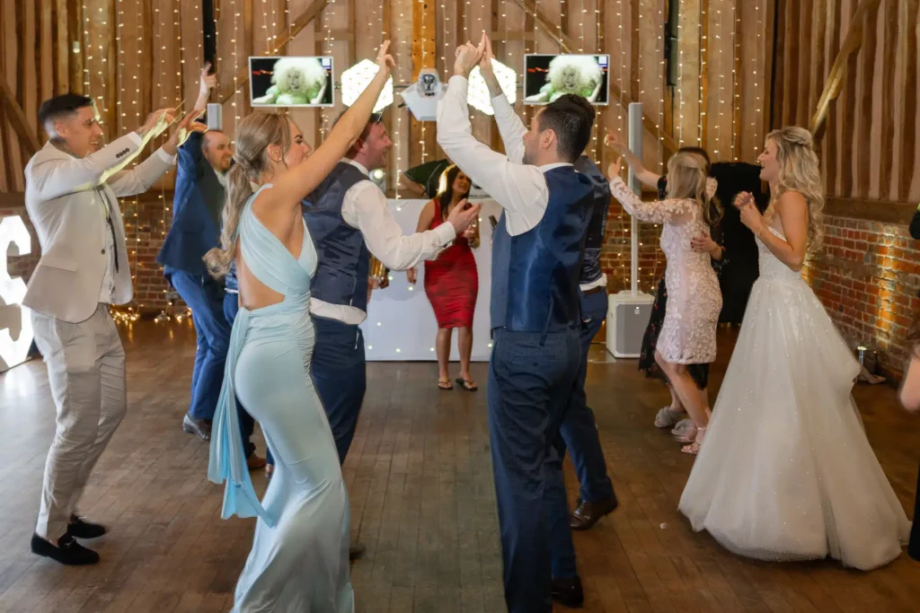 Wedding dance floor in barn venue with fairy light ceiling, bride visible and LED cube lighting