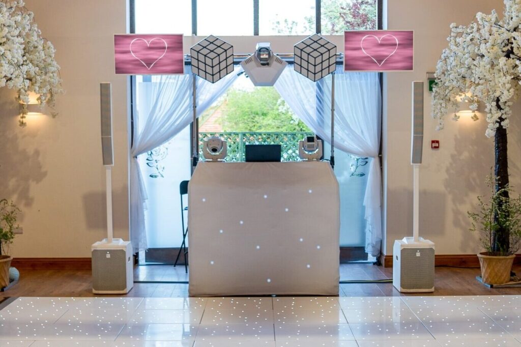 Wedding DJ booth setup on white starlit dance floor with cherry blossom trees and chandelier