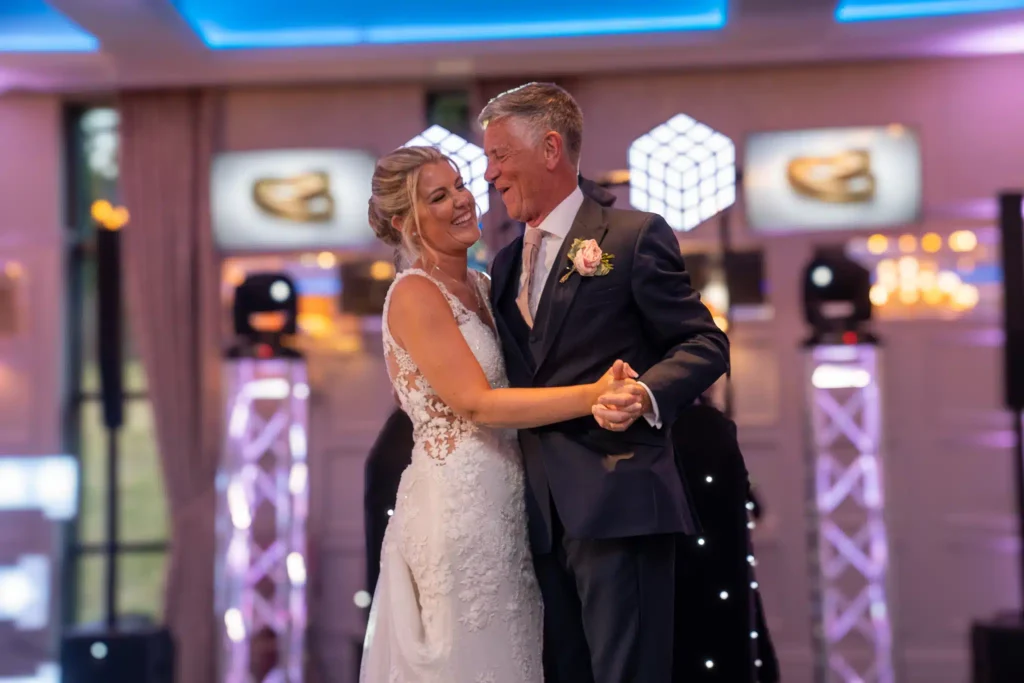 Bride and groom first dance under LED truss with cube lighting at indoor wedding venue
