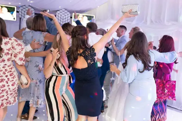 Wedding marquee reception with star cloth ceiling and crowd dancing with hands raised