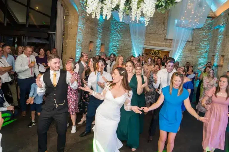 Wedding first dance with bride and groom in stone barn venue under a floral chandelier ceiling
