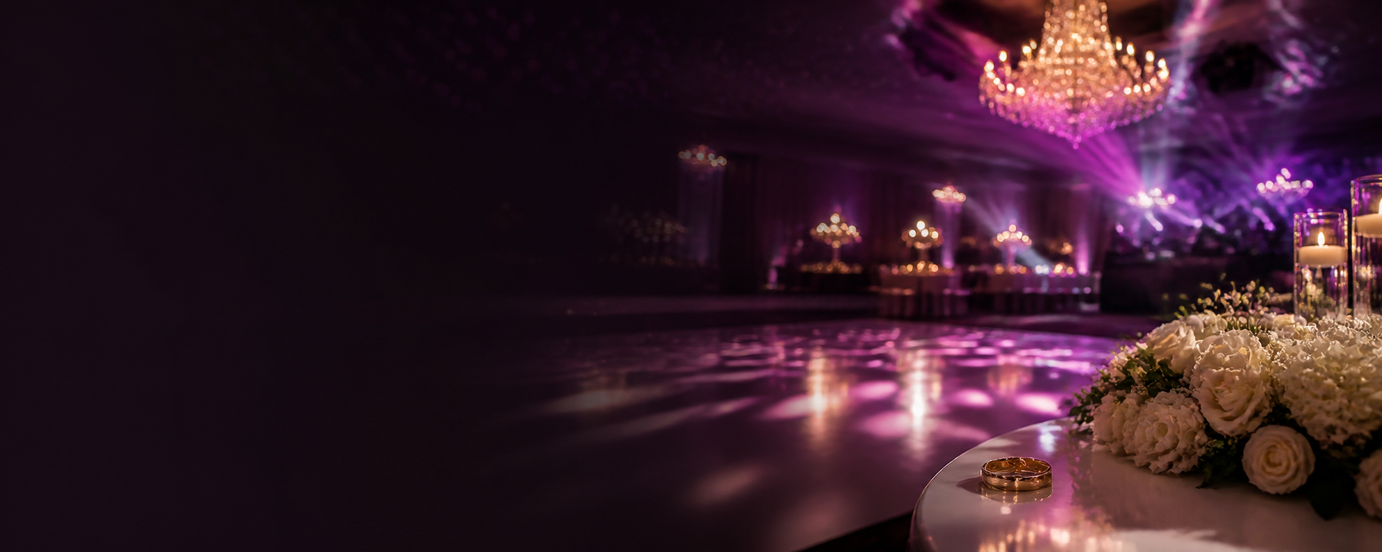 Elegant wedding reception with purple lighting, chandelier, flowers and wedding rings