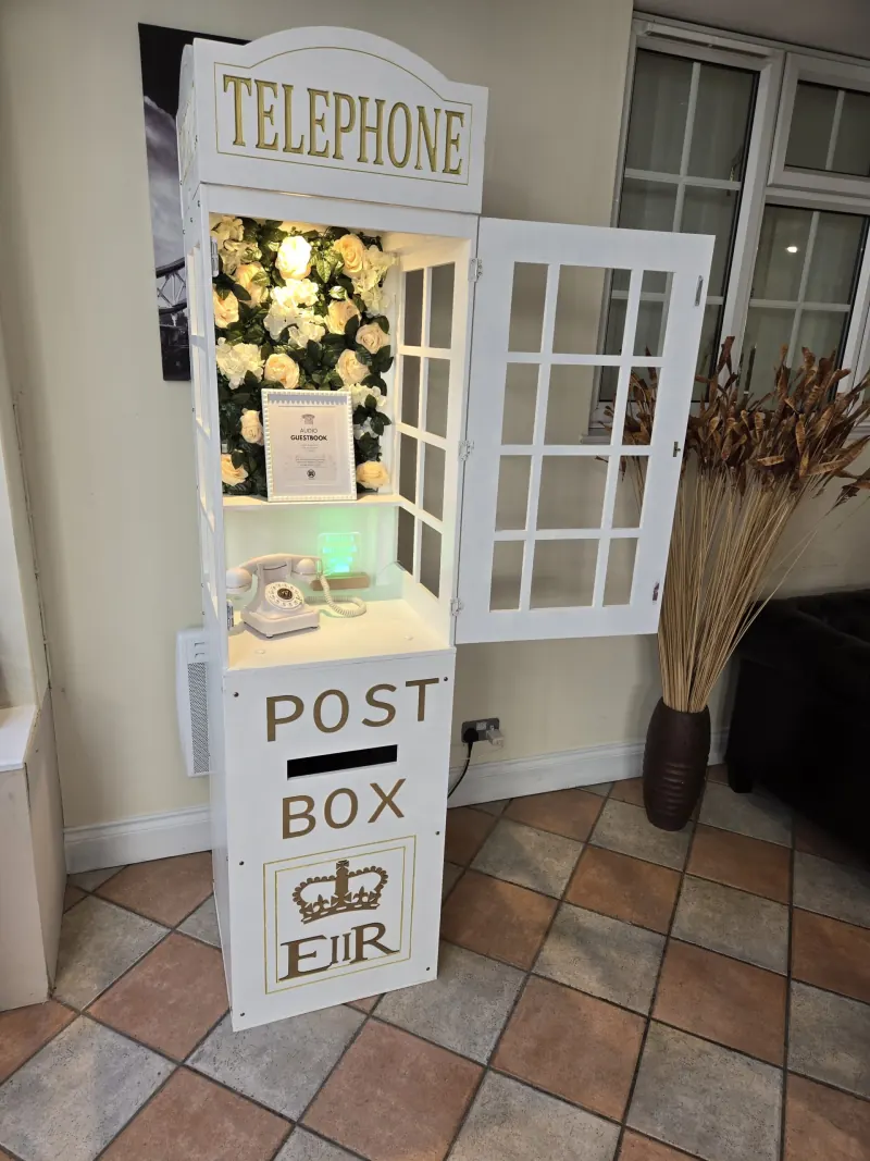 White audio guestbook telephone box with cream rose flower wall at a wedding