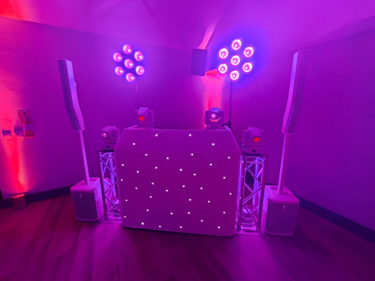 White starcloth DJ booth, white speakers and pink-purple lighting for an anniversary at Bedfont Sports Club